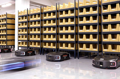 Black mobile robots carrying shelfs that contain cardboard totes