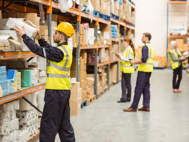 Workers in yellow safety vests and hard hats picking boxes from warehouse shelves